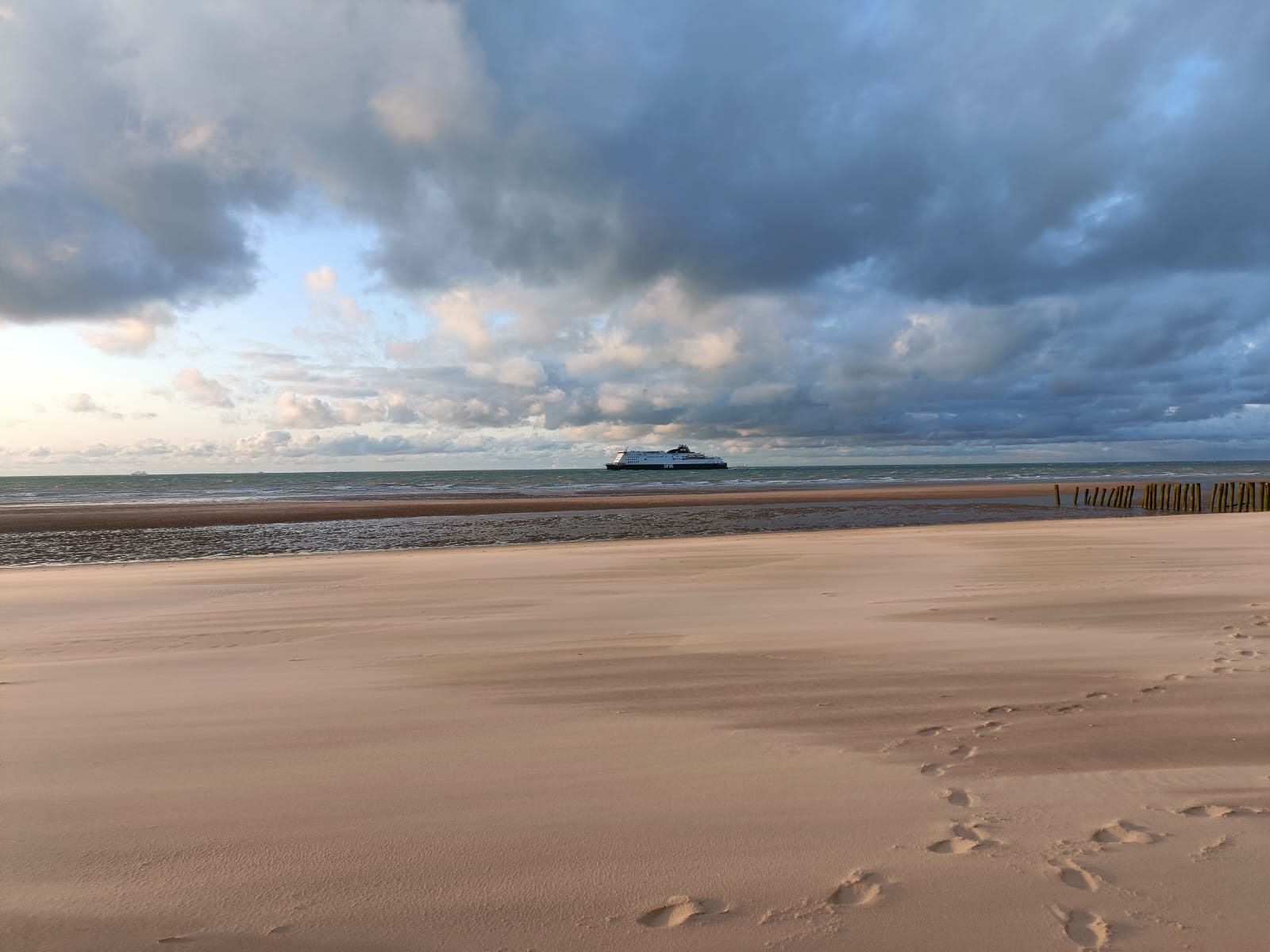 Voetstappen in het zand op het strand bij zonsondergang
